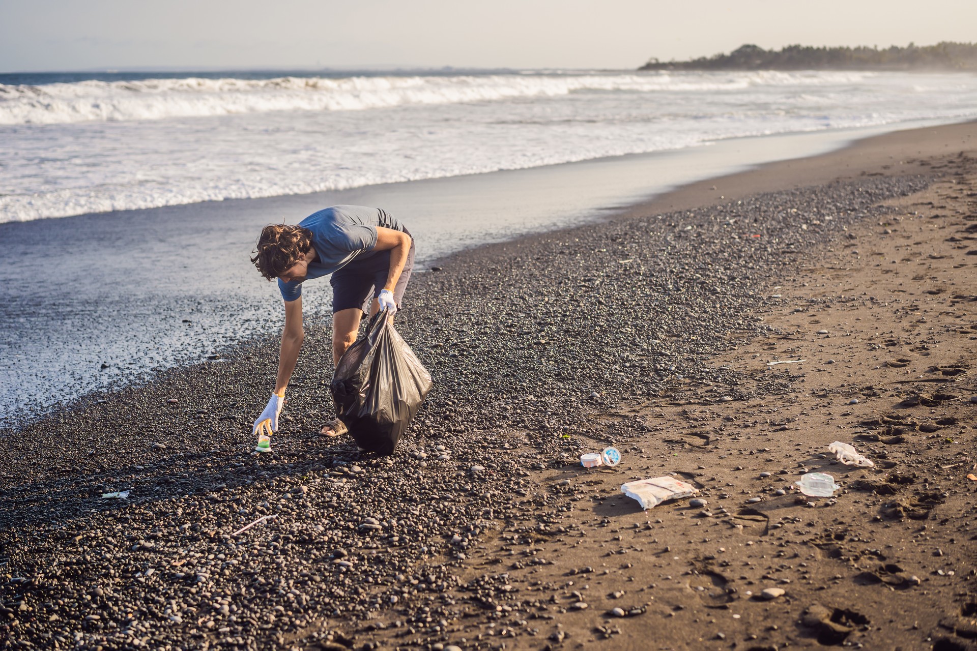 Young man cleaning up the beach. Natural education of children